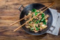 Traditional chinese mongolian beef stir fry in chinese cast iron wok with cooking chopsticks, wooden background. Top Royalty Free Stock Photo