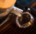 Traditional Chinese Tea Ceremony. Black or Red Tea pouring From Glass big Teapot into Glass Chahai on dark Wooden Table