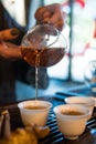 Traditional Chinese Tea Ceremony. Black or Red Tea pouring into White pial cup on dark Table background Royalty Free Stock Photo