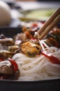 Traditional Chinese wooden chopsticks with mussels on the background of rice noodle dishes with seafood. Royalty Free Stock Photo