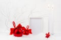 Traditional christmas background with blank photo frame mockup, burning candles, rich red glossy balls with satin ribbons, bows. Royalty Free Stock Photo