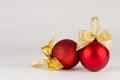 Traditional christmas background in modern simplicity style - rich shiny red balls with gold bows on white table, closeup.