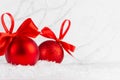Traditional christmas decoration - red glitter balls with ribbons, bows, closeup with blur in snow, white elegant soft light fairy Royalty Free Stock Photo