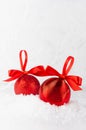 Traditional christmas decoration - red ribbed balls with ribbons, bows, closeup in snow, white elegant soft light fairy winter.