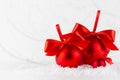 Traditional christmas decoration - three red glossy balls with satin ribbons, bows, closeup in snow, white elegant soft light.