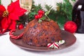 Traditional Christmas pudding with holly on top and Christmas decoration on the background Royalty Free Stock Photo