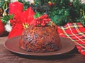 Traditional Christmas pudding with holly on top on the wooden background Royalty Free Stock Photo