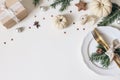 Traditional Christmas table place setting. Golden cutlery, porcelain plate, fir tree branches, gift box, pine cones and Royalty Free Stock Photo