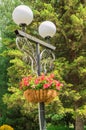 Traditional city lantern with decorative hanging basket with beautiful flowers in the Park on the background of green trees on a Royalty Free Stock Photo