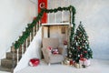 Traditional classic Christmas tree and beige armchair, stairs to the second floor in the living room or dining room