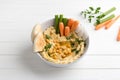 Traditional classic hummus with cumin, parsley, olive oil, served with vegetables and pita bread on a white background