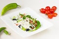 Traditional classic Shopska salad with tomatoes, peppers, cucumbers and cheese in white dish on white wooden table. Bulgarian cuis Royalty Free Stock Photo