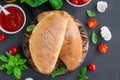 Traditional closed Italian calzone pizza with tomato sauce, mozzarella cheese and mushrooms on a board on a dark background.