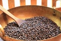 Traditional coffee beans roasting in metal basin with spatula.