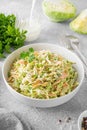 Traditional cole slaw salad in a bowl on a gray concrete background. Salad with cabbage, carrot and mayonnaise sauce.