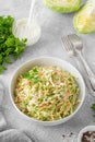 Traditional cole slaw salad in a bowl on a gray concrete background. Salad with cabbage, carrot and mayonnaise sauce.