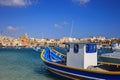 Traditional fishing boats, luzzu, anchored at Marsaxlokk, Malta. Blue sky and village background. Close up view. Royalty Free Stock Photo