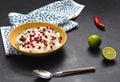 Traditional curd rice in a yellow plate on a dark background. Spoon, lime, hot red pepper.