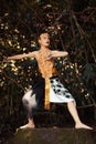 A Traditional dancer with golden clothes and a golden crown posing bravely in the jungle