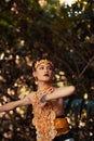 A Traditional dancer with golden clothes and a golden crown posing bravely in the jungle