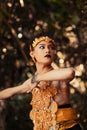 A Traditional dancer with golden clothes and a golden crown posing bravely in the jungle