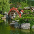 Traditional Details of Classical Japanese Zen Garden. Arched ornamental wooden red footbridge and scenic pond