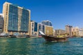 A traditional dhow cargo vessel cruises past modern buildings lining the Dubai Creek in the UAE Royalty Free Stock Photo