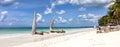 Traditional dhows on a beach on the coast of Zanzibar. Boats in turquoise ocean and blue sky, panorama. Royalty Free Stock Photo