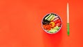 Traditional dish of Korean cuisine. Bibimbap with beef, vegetables and egg on coral background. Top view. Royalty Free Stock Photo