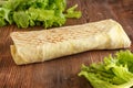 A traditional dish of vegetables wrapped in lavash. Shaurma on a wooden background.