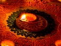 Traditional diya lamp lit on colorful rangoli