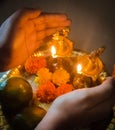 Traditional diya with flowers, fruits and women hands