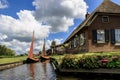 Traditional dutch brick houses with lush green lawns on a water canal in Giethoorn village, Netherlands