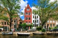 Traditional dutch houses and boats on canal in the most romantic city. Tranquil scene of Amsterdam street in summer. Netherlands.