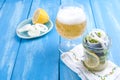 Traditional Dutch marinated herring with lemon and onions in a jar. Fresh Belgian beer in a glass. Seafood on a blue background. Royalty Free Stock Photo