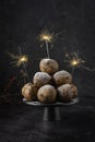 Traditional Dutch oliebollen (deep fried dough balls) on black background with sparkles, served on New Years Eve