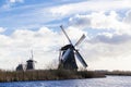 Traditional dutch windmill near the canal. Netherlands. Old windmill stands on the banks of the canal, and water pumps. White clou Royalty Free Stock Photo