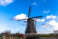 Traditional dutch windmill near the canal. Netherlands. Old windmill stands on the banks of the canal, and water pumps. White clou Royalty Free Stock Photo