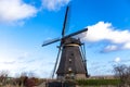 Traditional dutch windmill near the canal. Netherlands. Old windmill stands on the banks of the canal, and water pumps. White clou Royalty Free Stock Photo