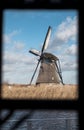 Traditional dutch windmill near the canal. Netherlands. Old windmill stands on the banks of the canal, and water pumps. White clou Royalty Free Stock Photo