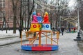 Traditional Dymkovo toy three women in headscarves as art object and Children`s carousel at Russian national festival `Shrove` in