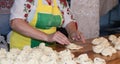Traditional east european woman in authentic clothing kneading bread dough for