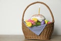 Traditional Easter cake with burning candle, dyed eggs and flowers in basket on table against white background. Space for text Royalty Free Stock Photo