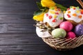 Traditional Easter cakes and eggs in wicker basket on dark table. Space for text Royalty Free Stock Photo