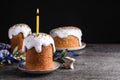 Traditional Easter cakes and one with burning candle on grey table against black background. Space for text Royalty Free Stock Photo
