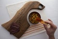 Traditional eastern european food setup. Walnut cutting board, bean soup,  sausage and spices. Bulgaria, balkan food. Hand holding Royalty Free Stock Photo