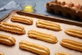 Traditional eclairs or profiterole preparing with eggs on baking sheet