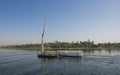 Traditional Egyptian felluca traveling on Nile river through rural landscape