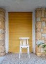 Traditional Egyptian white wooden chair over in front of bricks stone wall and yellow roll-up door