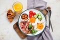 Traditional Englis breakfast plate with bacon strips, sunny side up eggs, vegetables and cake on light background Royalty Free Stock Photo